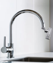 AERO Vital Wasserhahnaufsatz montiert an einem verchromten Küchenwasserhahn über einer Spüle in heller Umgebung