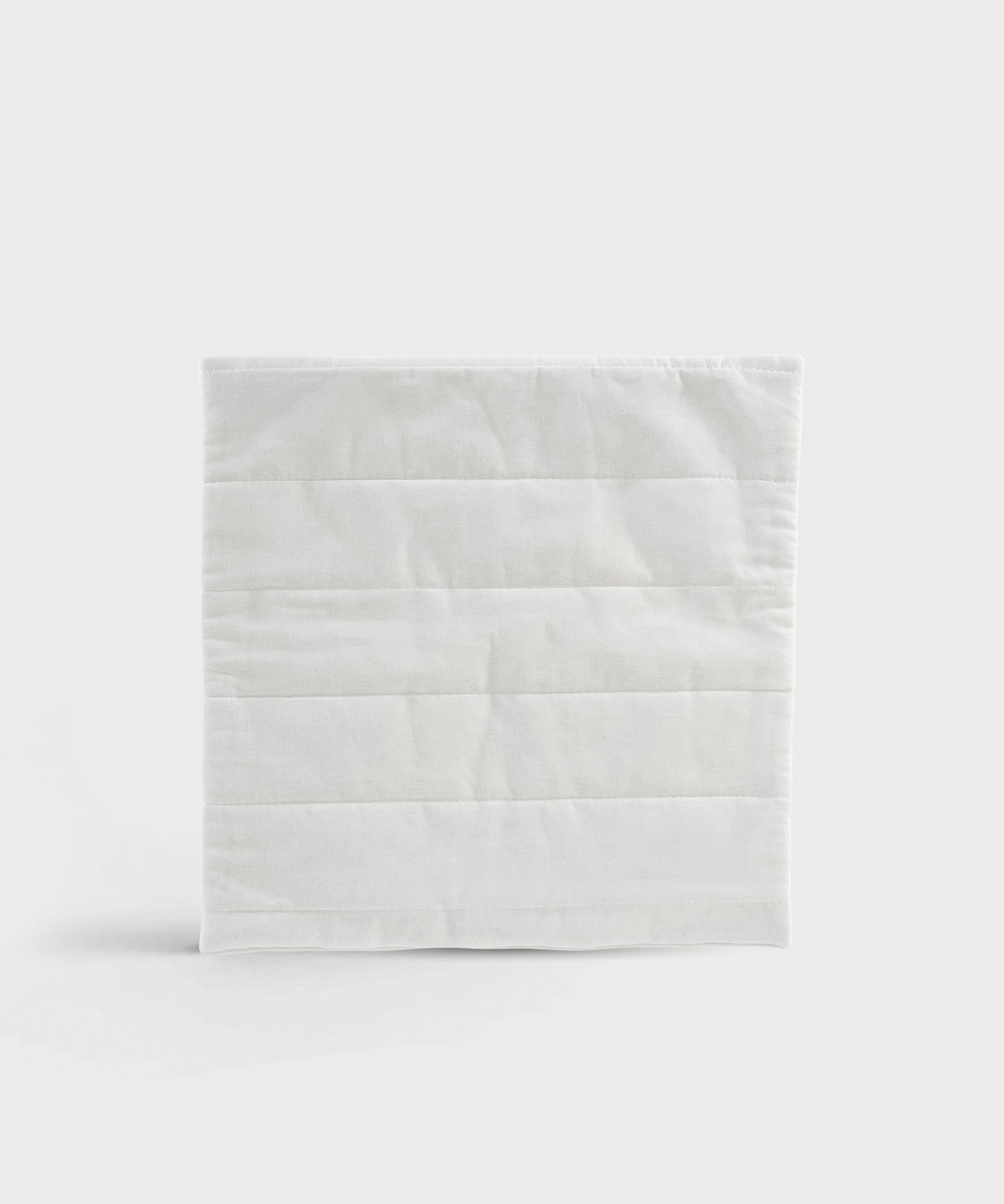 Quadratisches Grounding Relax Pad in weißer Textiloptik mit horizontalen Steppnähten auf neutralem Hintergrund