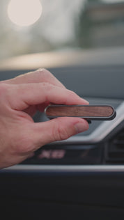 Hand hält das ProEnergetic E-Protect Car und schiebt das Gerät in den Lüftungsschlitz eines Autos im Innenraum