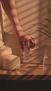 Hand steckt im Innenraum ein E-Protect S90 Steckelement in eine Wandsteckdose neben brennenden Kerzen