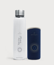 Water Vitalizer Glastrinkflasche mit Edelstahlverschluss neben abnehmbarer dunkelblauer Schutzhülle mit Tropfensymbol auf hellem Hintergrund